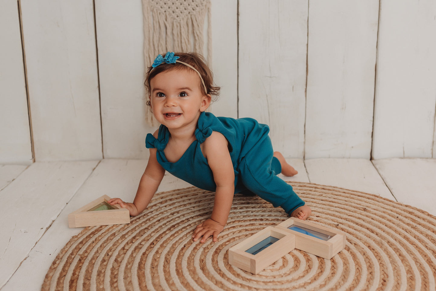 baby girl sits on the bohemian mat playing with wooden blocks whilst wearing her handmade teal blue lounge comfy romper adjustable straps cosy winter clothing