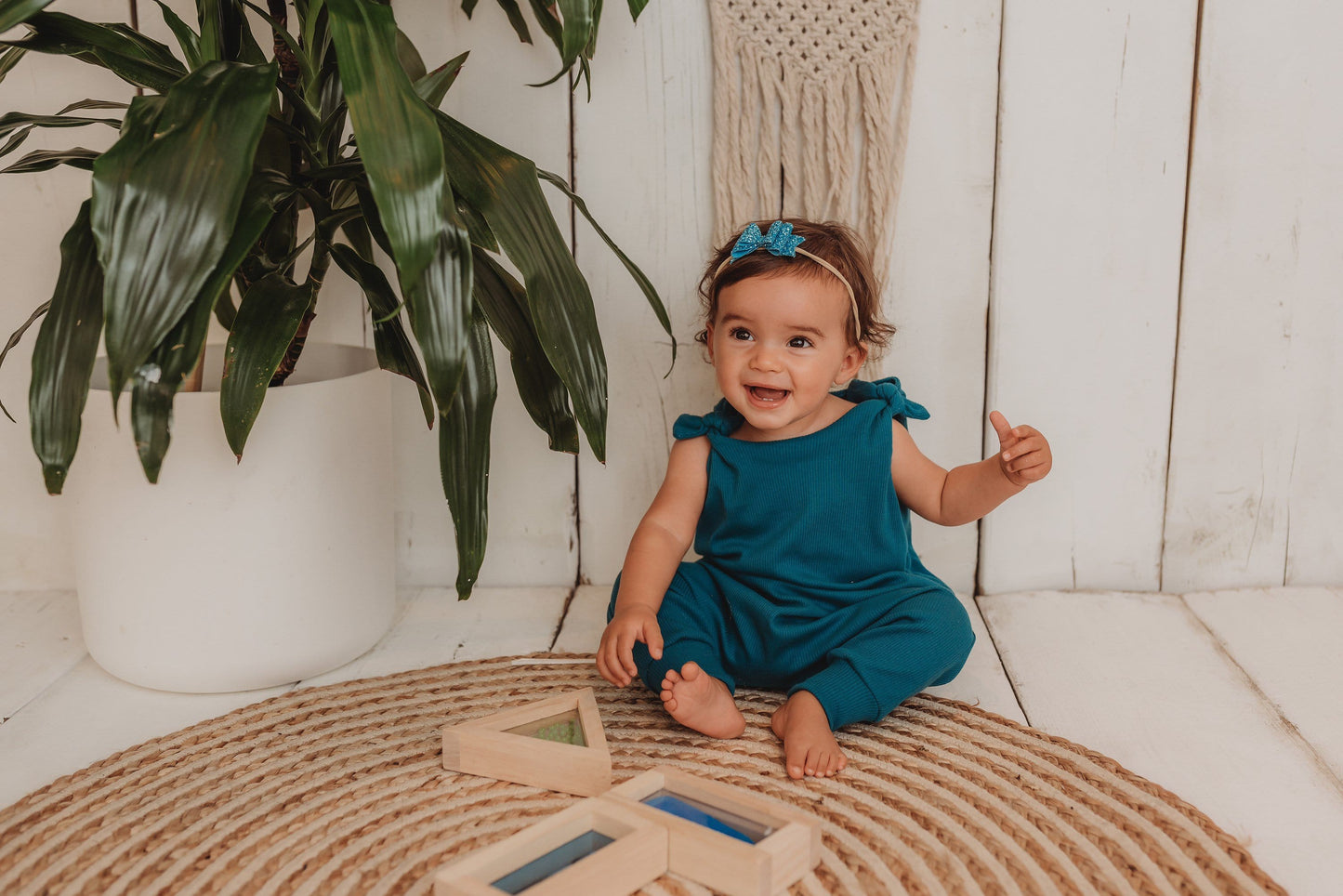 baby girl sits on the bohemian mat playing with wooden blocks whilst wearing her handmade teal blue lounge comfy romper adjustable straps cosy winter clothing